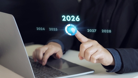 homme derrière son ordinateur qui touche du doigt la date 2026
